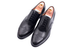 Eleganckie obuwie koloru czarnego typu brogues z gumową podeszwą. Szyte metodą ramową.